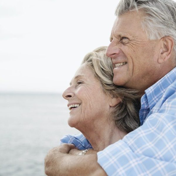 Senior couple embracing at harbor, smiling